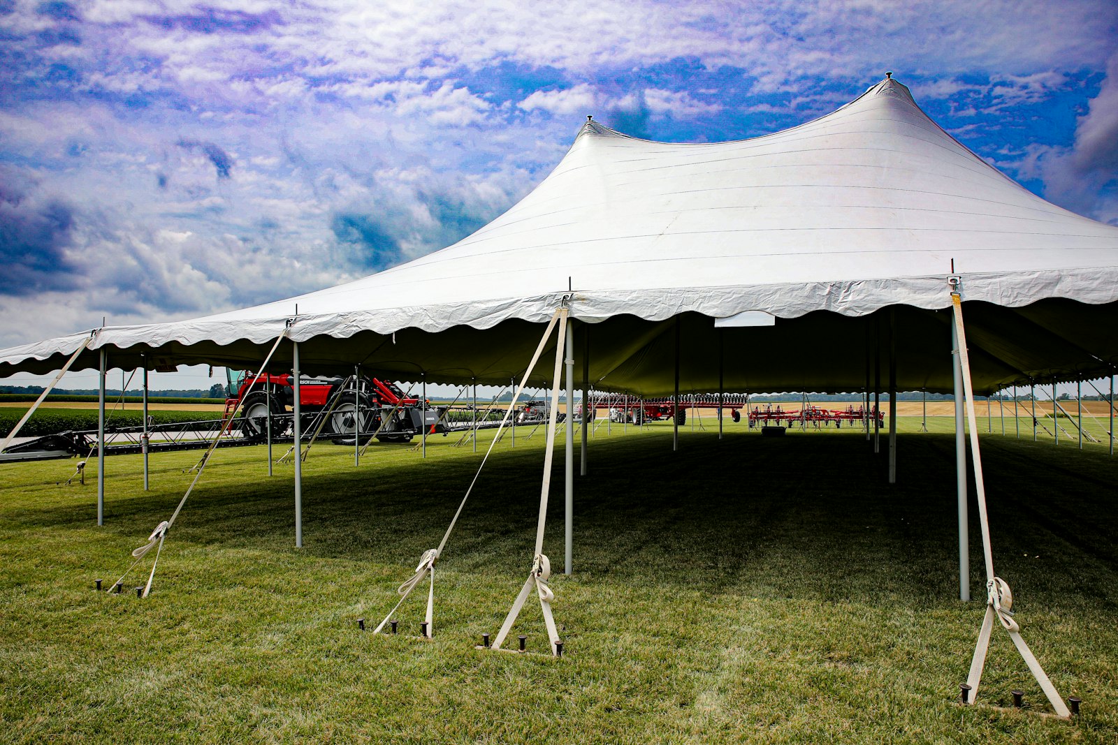 Large white pole tent set up on a grass field for an outdoor event